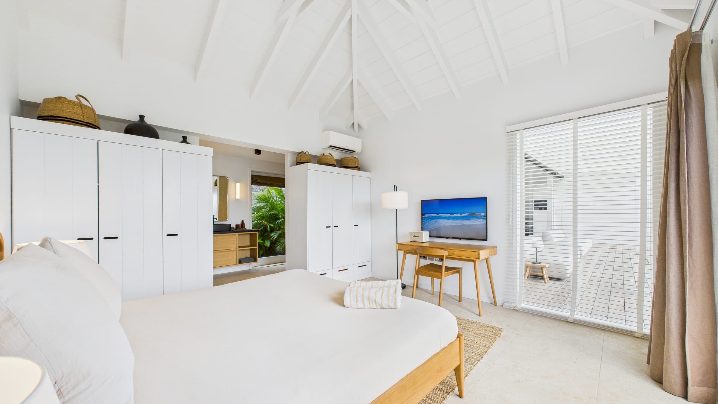 Second bedroom under a peaked white ceiling, oak desk and a glimpse of the ensuite through the open doorway