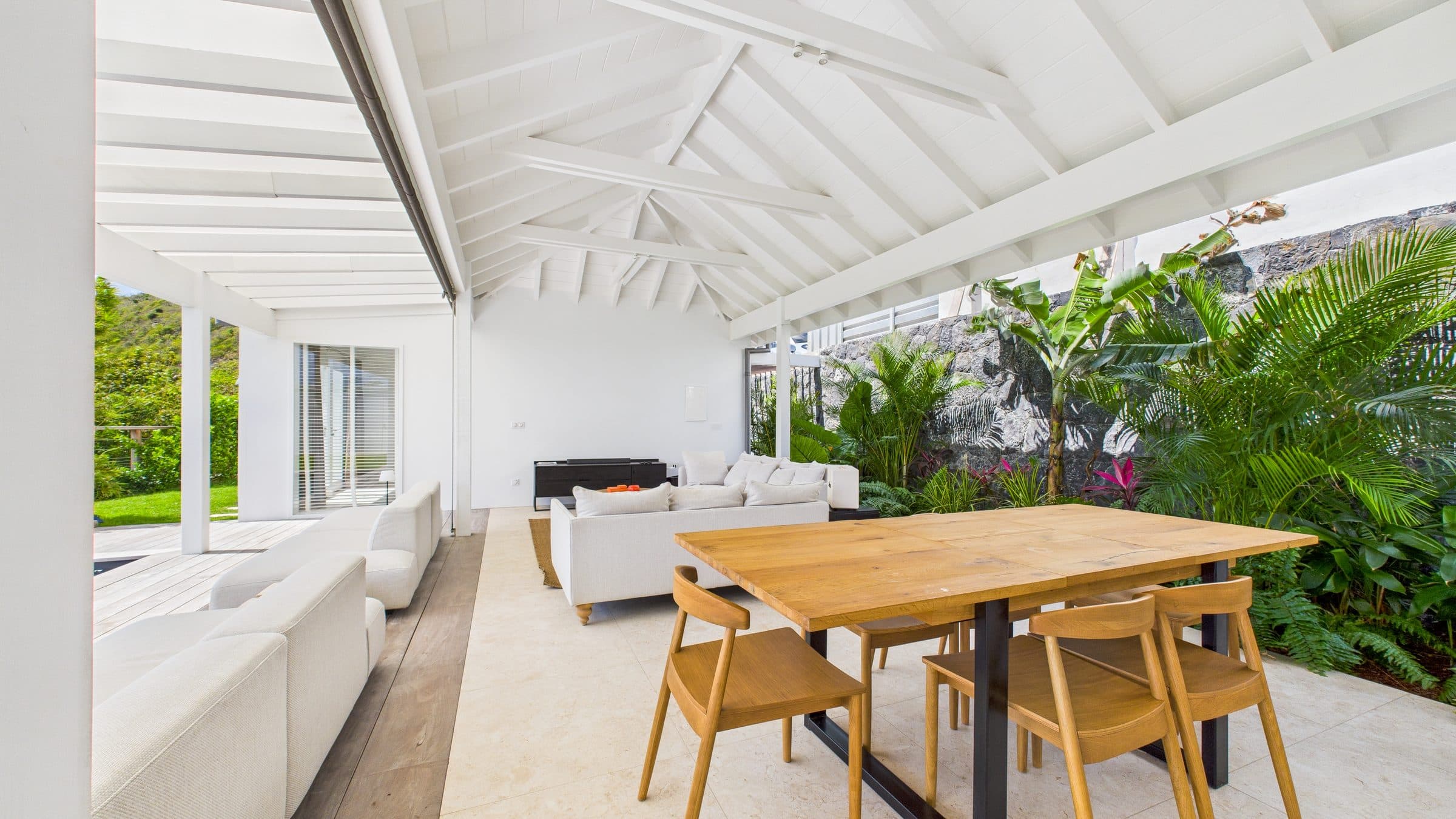 Combined living and dining pavilion under a vaulted timber ceiling, oak table seating six beside the lounge area