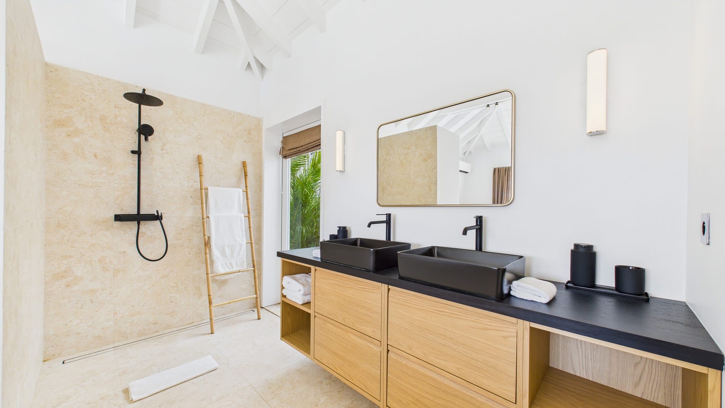 Master ensuite with a walk-in stone-tiled shower and double black vessel sinks set into an oak vanity